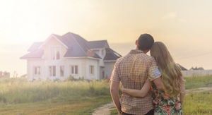 A man and a woman are standing in front of a house.