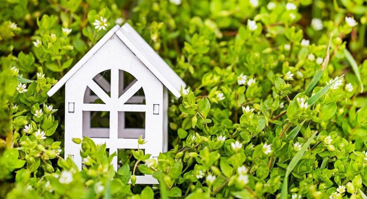 A small white house is sitting in the grass.