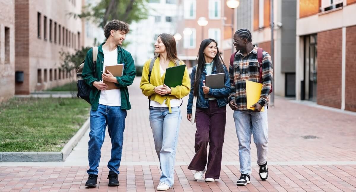 A group of young people are walking down a sidewalk.