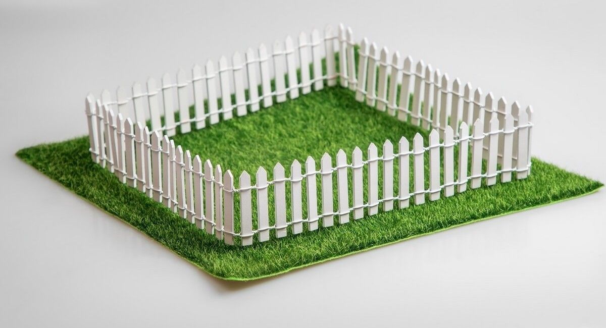 A white picket fence is sitting on top of a lush green field.