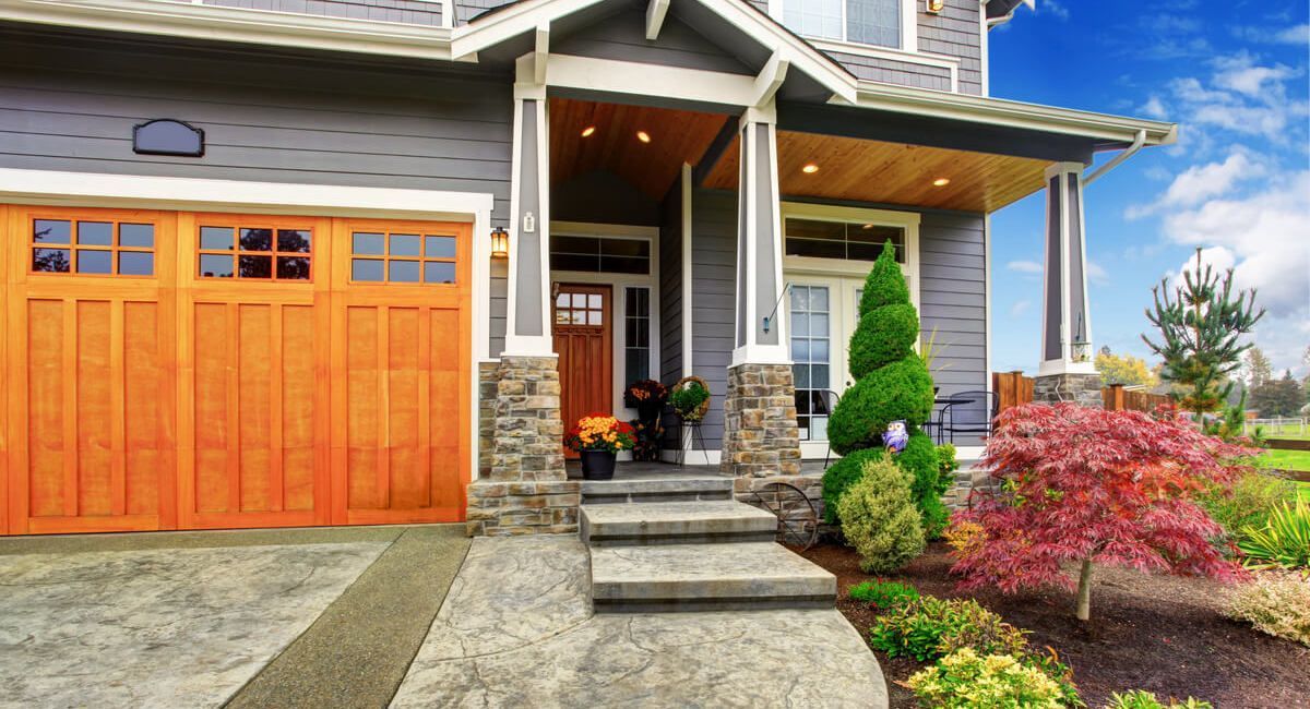 A large house with a wooden garage door and a porch.