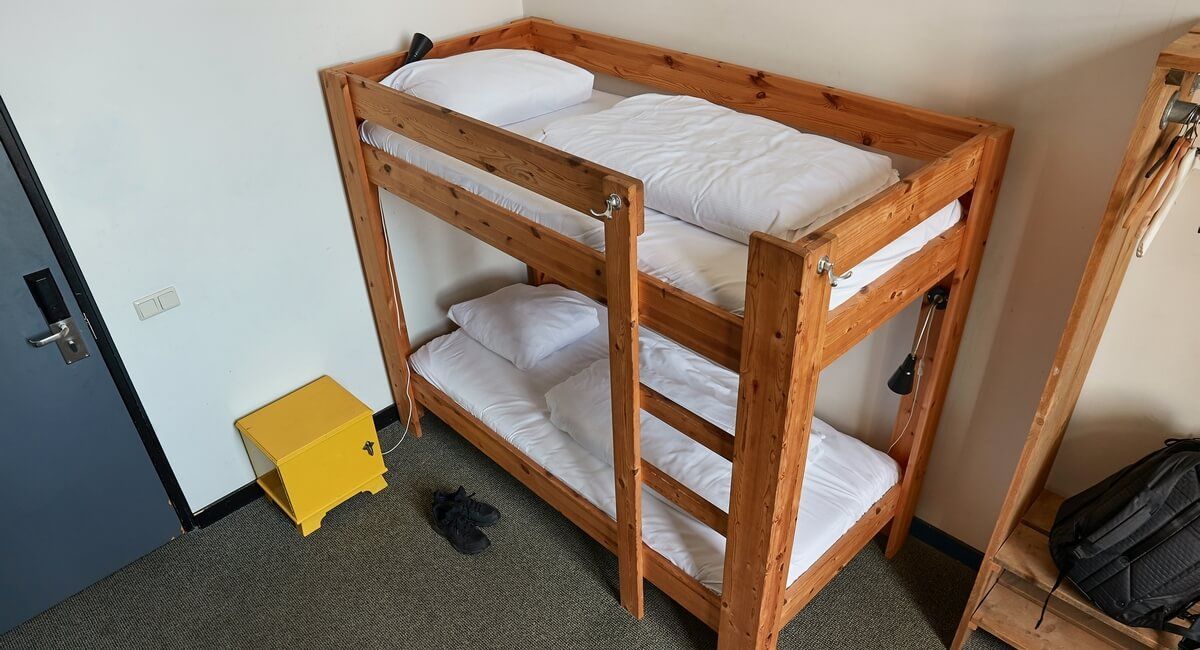 A bunk bed is sitting in a room next to a yellow stool.