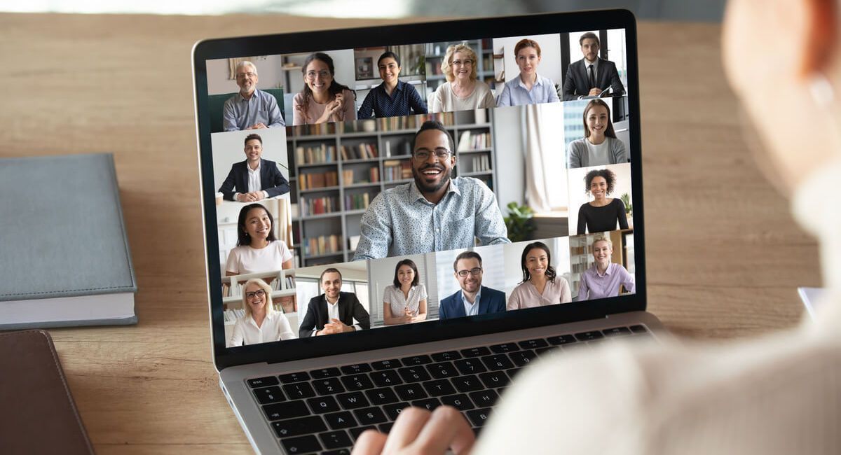 A person is using a laptop computer to have a video call with a group of people.