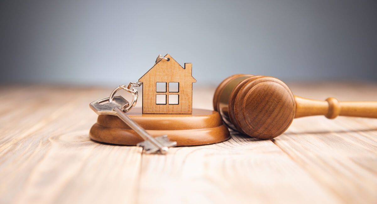 A wooden house , keys and a wooden gavel on a wooden table.