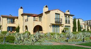 A large house with a lot of windows is surrounded by a lush green lawn.