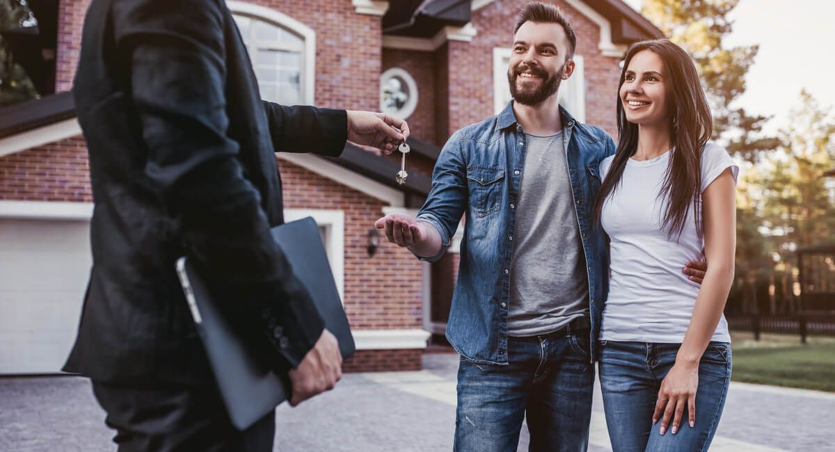 A man is giving a couple keys to their new house.