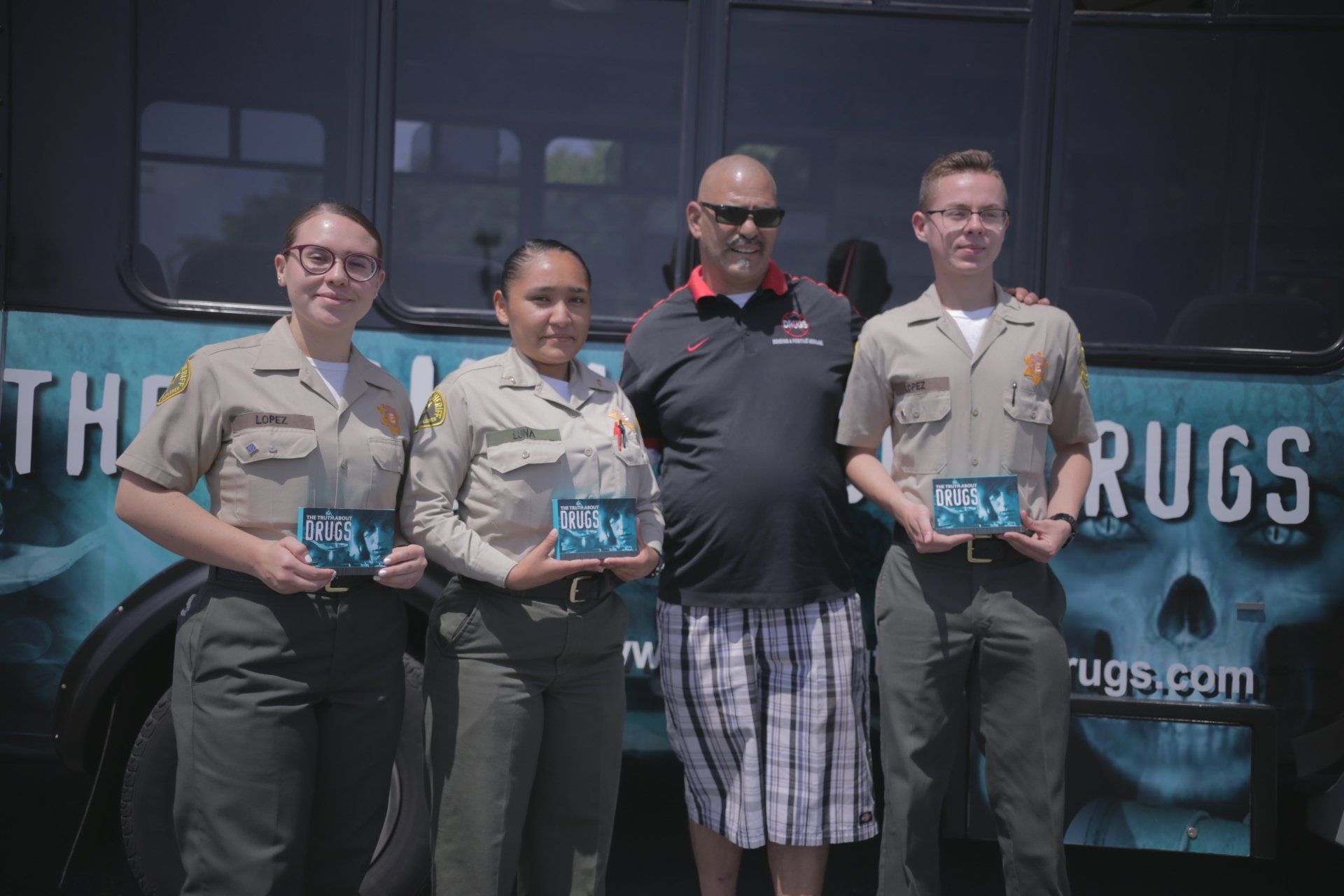 A group of people standing in front of a bus that says rugs