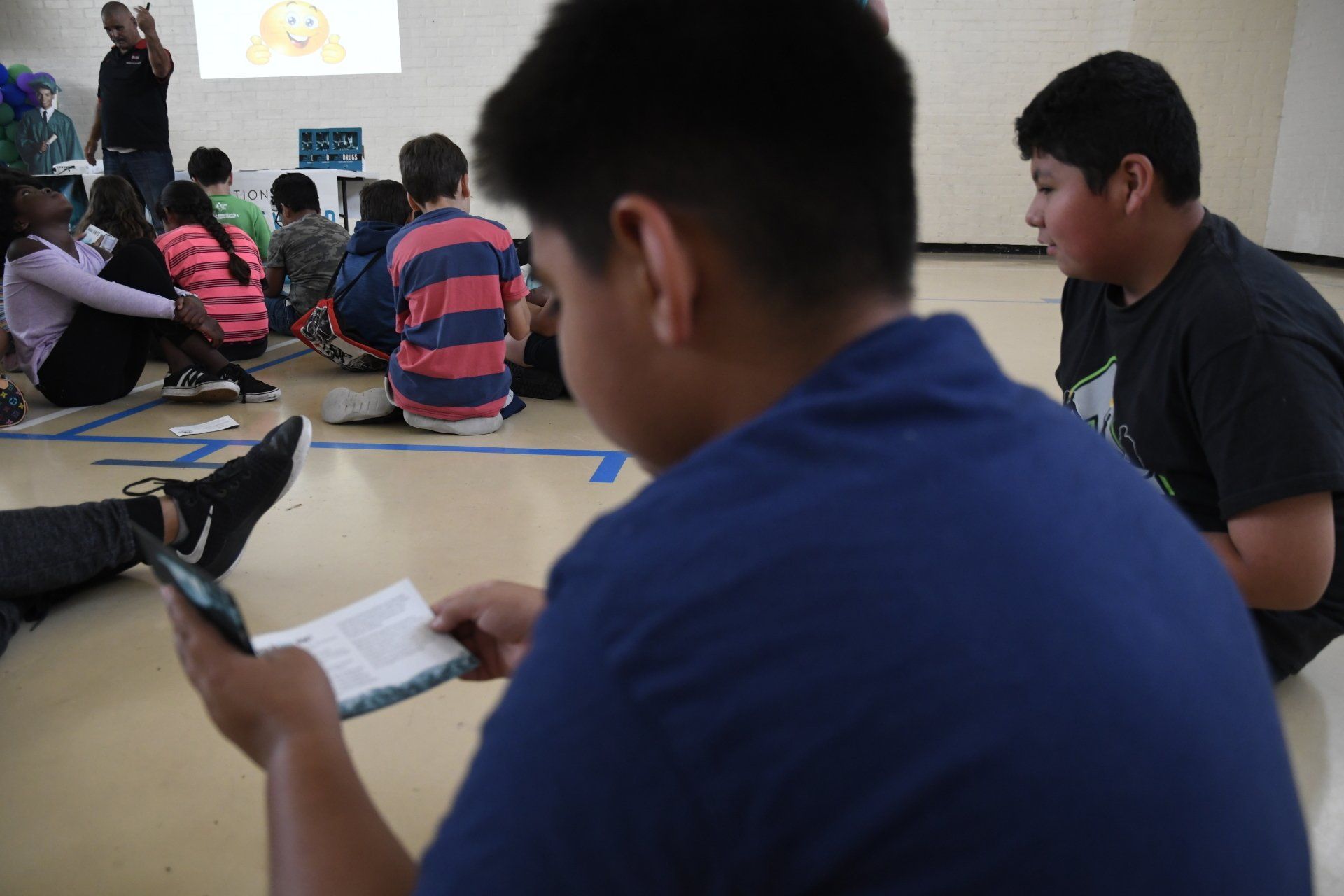 A group of children are sitting on the floor watching a presentation.