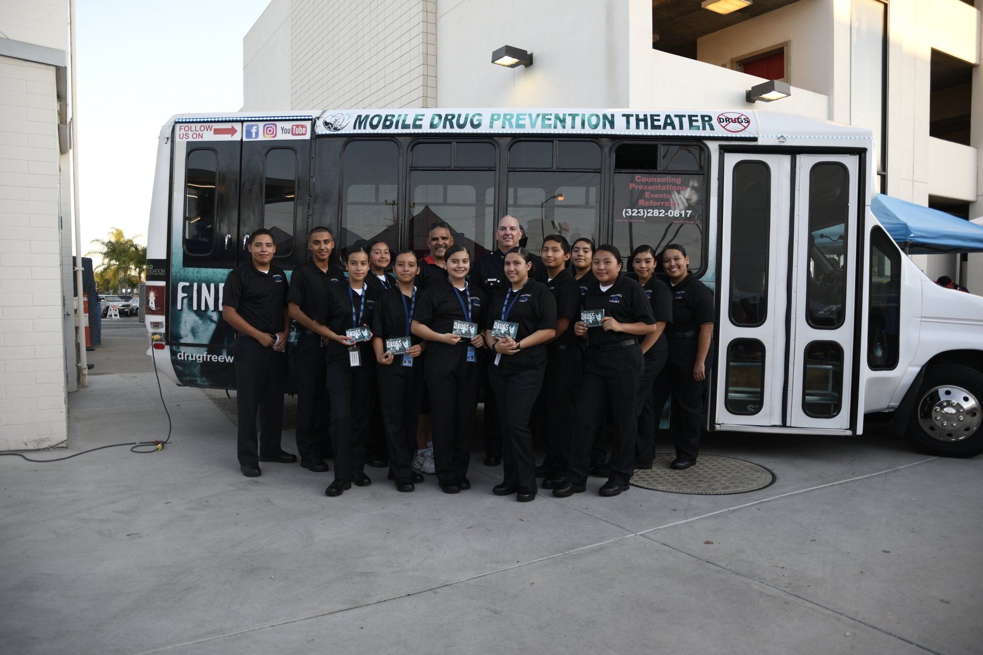A group of people standing in front of a bus that says prevention theatre