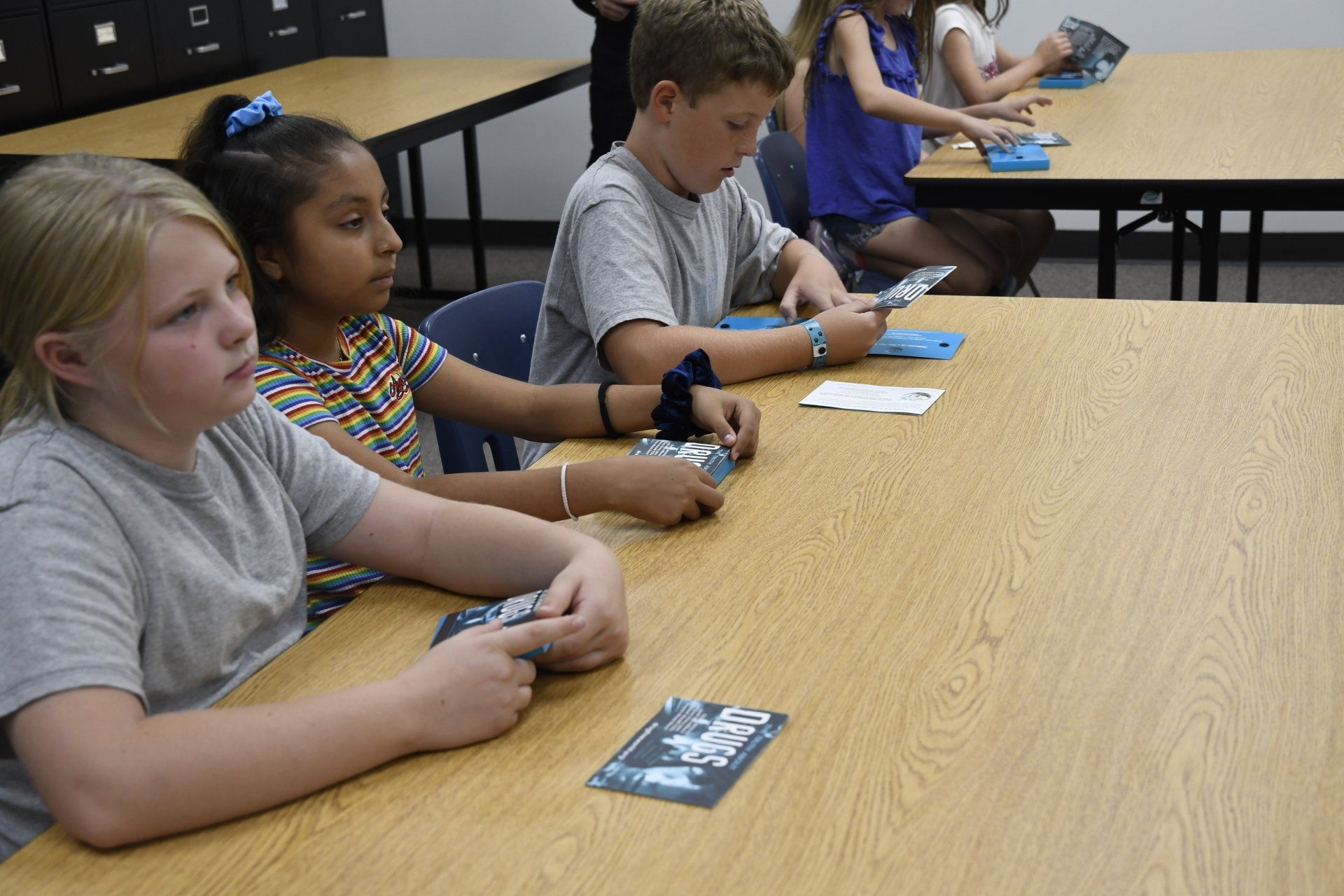 A group of children are sitting at a table playing cards.
