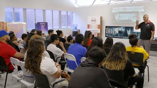 A man is giving a presentation to a group of people sitting in chairs.