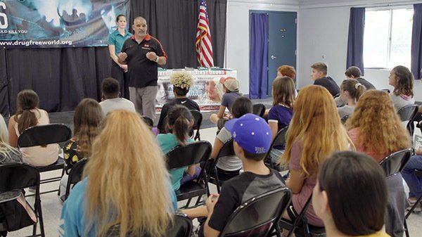 A group of people are sitting in chairs in front of a stage.