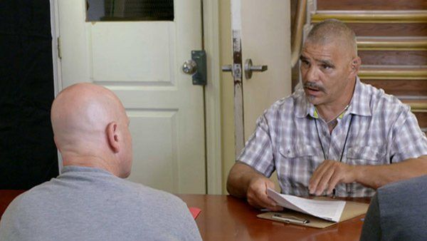Two men are sitting at a table talking to each other.