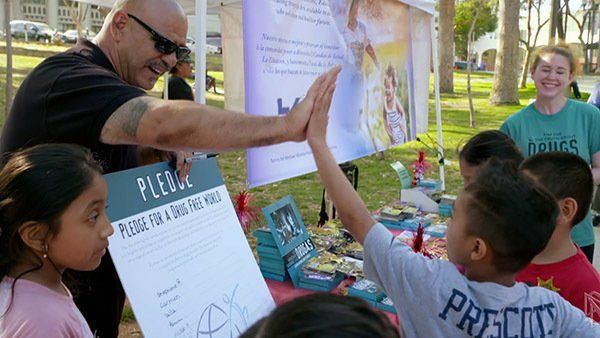 A man is giving a child a high five while holding a sign.