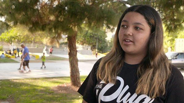 A young girl wearing a black shirt is standing in a park.