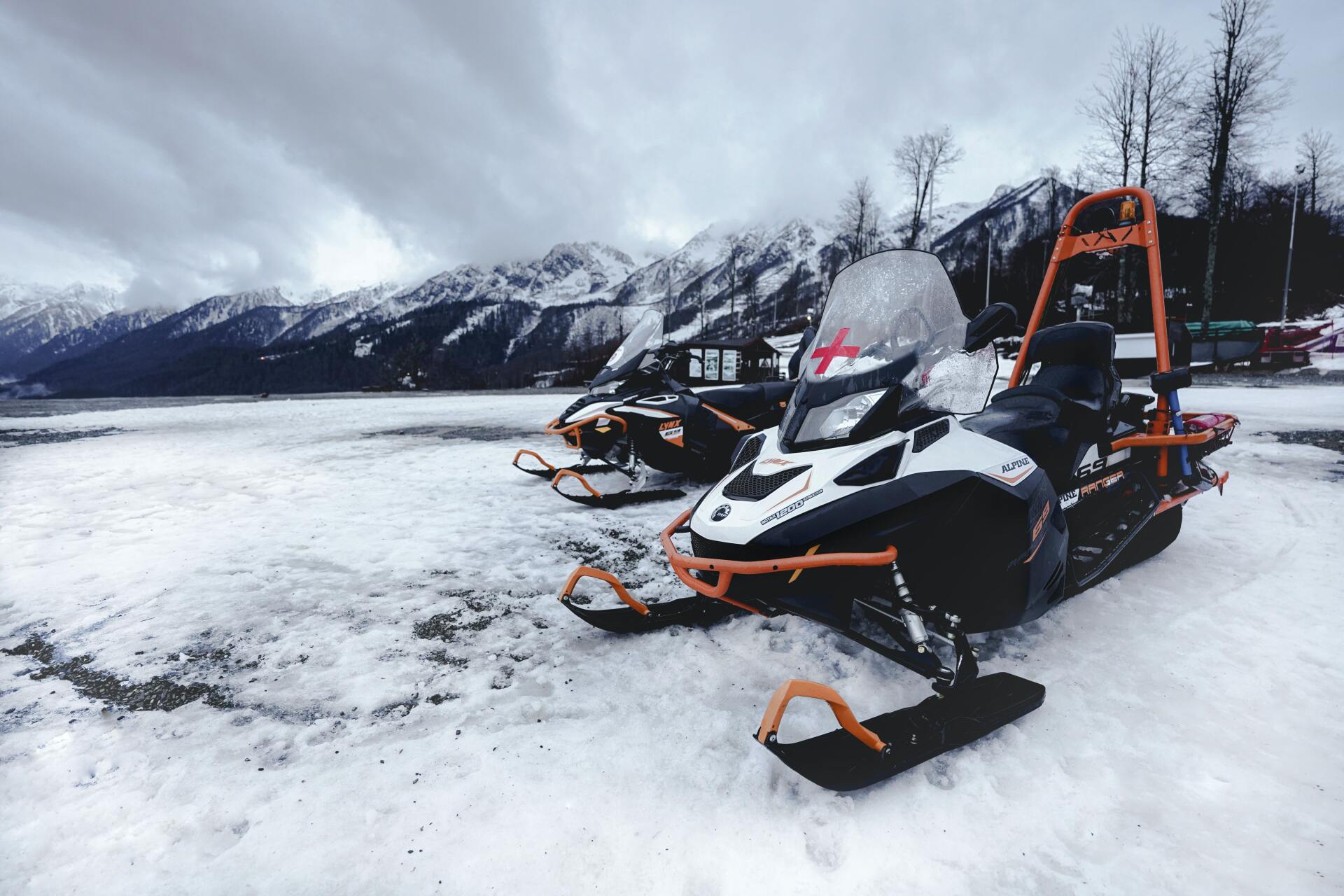 Snowmobile rider performing a jump trick in the mountains