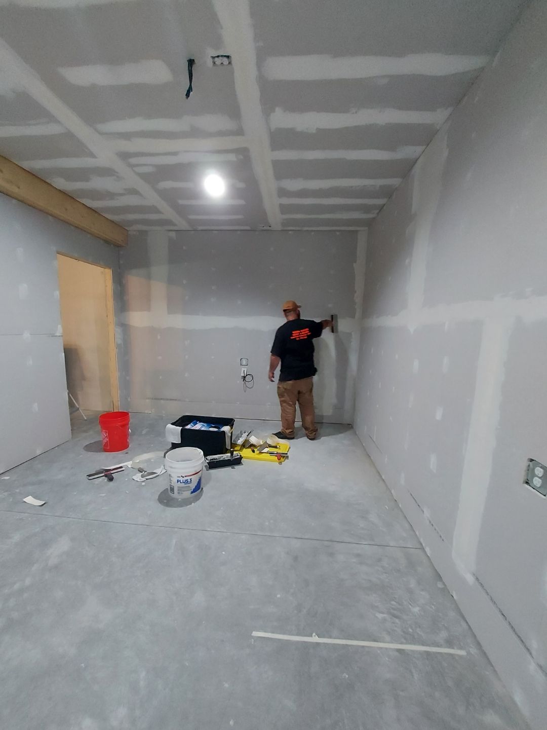 A man is standing in an empty room painting a wall.