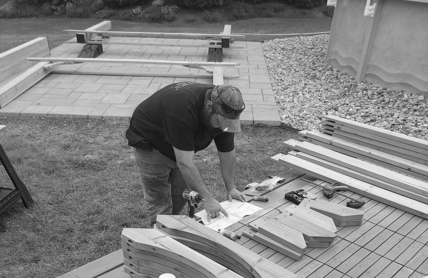 A black and white photo of a man cutting a piece of wood