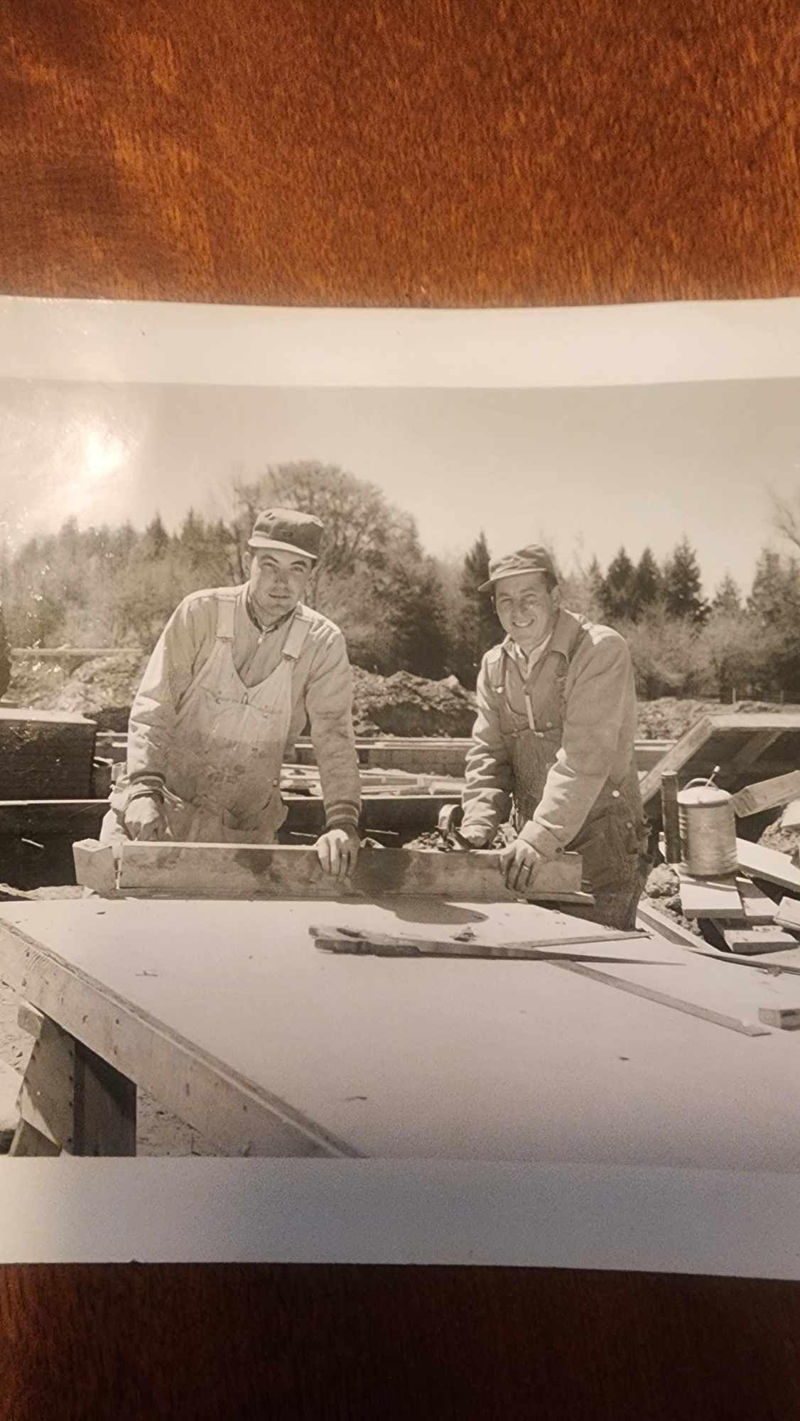 A black and white photo of two men working on a table.