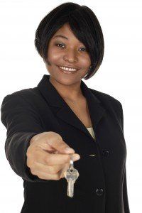 An attractive young business woman hands keys to viewer.