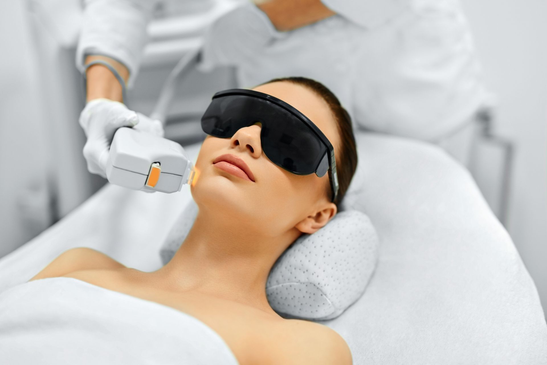A woman is getting a laser hair removal treatment on her face.