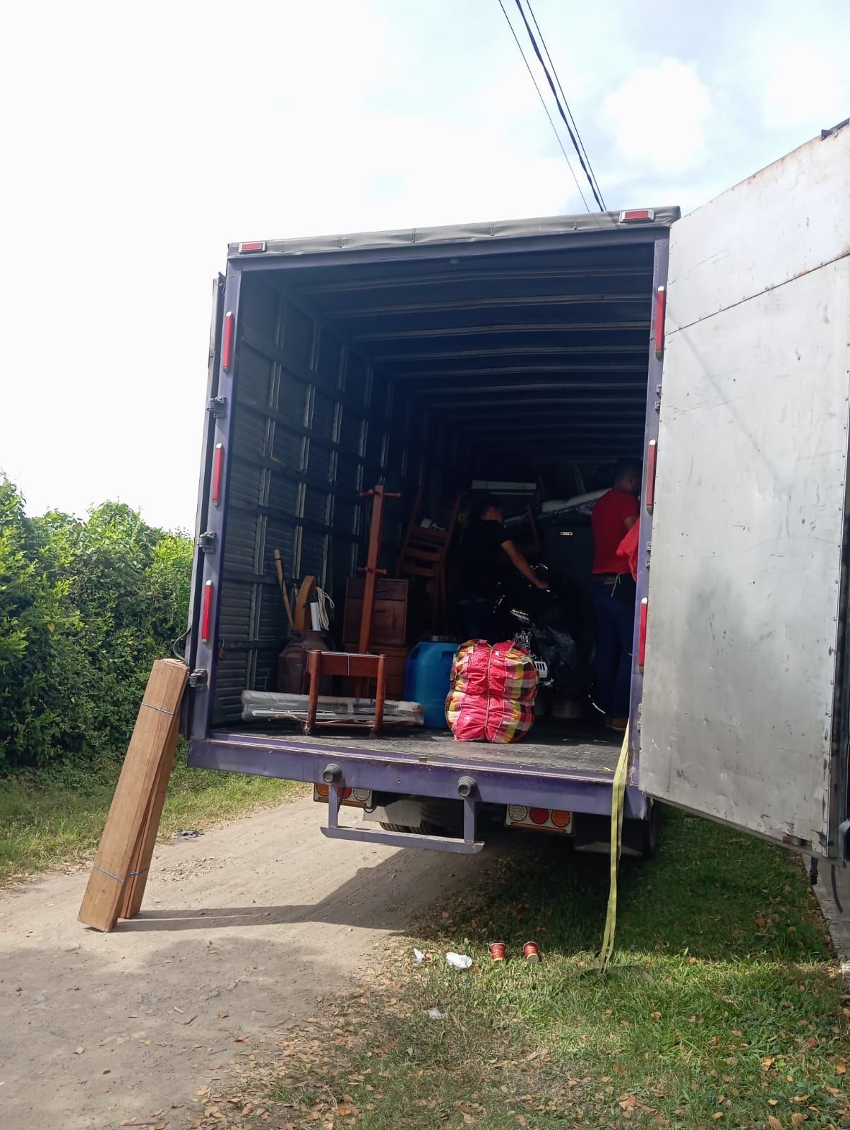 Un hombre está parado en la parte trasera de un camión en movimiento.