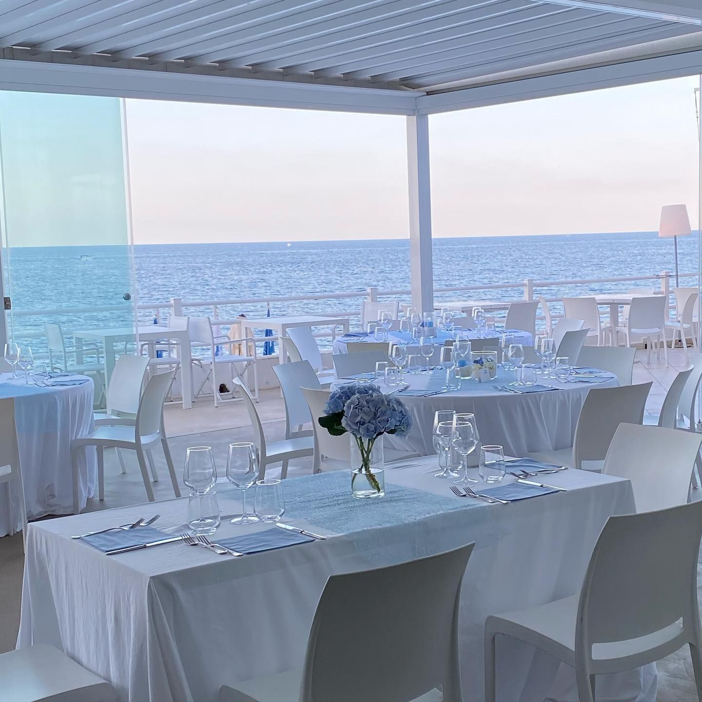 Coppia che si bacia sulla torta nuziale decorata con fiori e con l'oceano sullo sfondo.