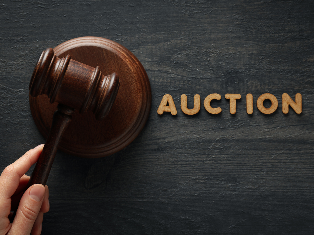 Gavel in hand next to words Auction