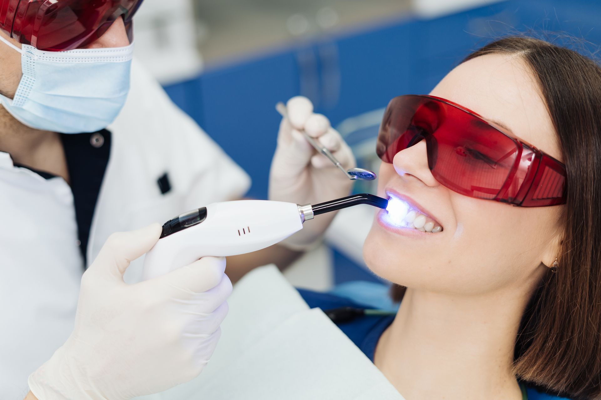 Patient wearing protective glasses receiving dental light teeth whitening treatment. Patient wearing protective glasses receiving dental light teeth whitening treatment.