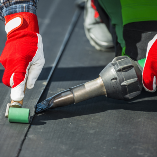 a worker is sealing an epdm roof with an adhesive