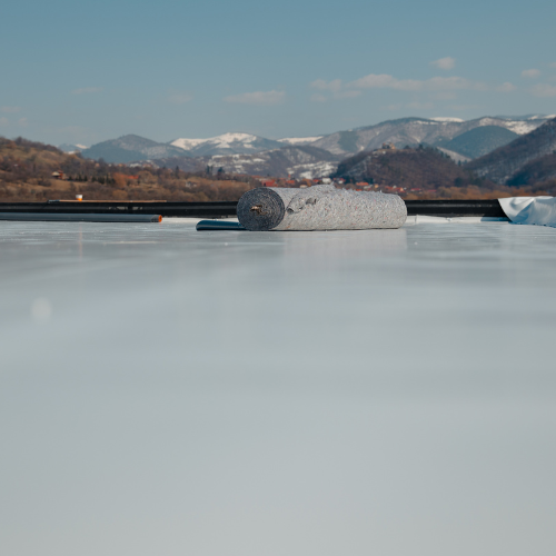 a roll of textile matting is sitting on top of a fitted pvc commercial roof