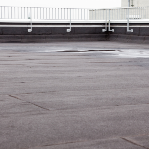 An a built-up roof with a railing and a fence in the background