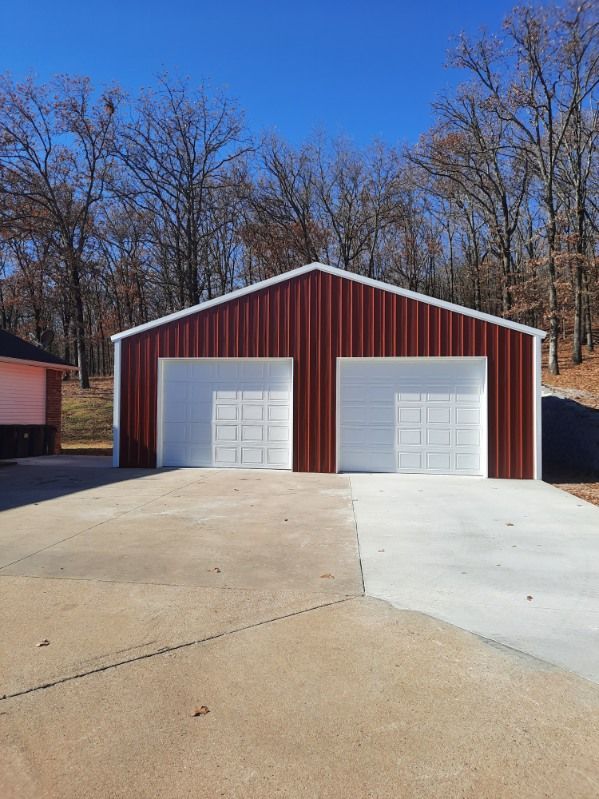 A red and white garage with two garage doors and a driveway.