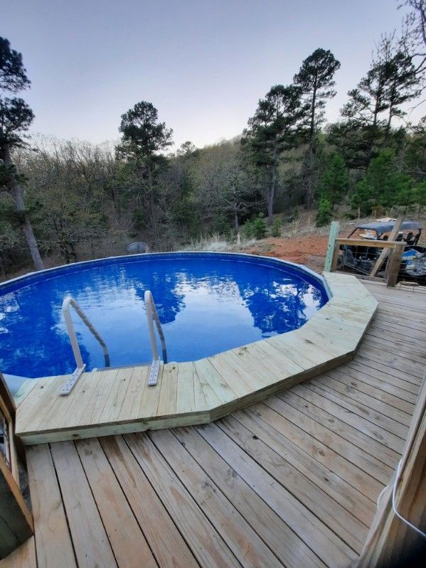 A swimming pool is sitting on top of a wooden deck.