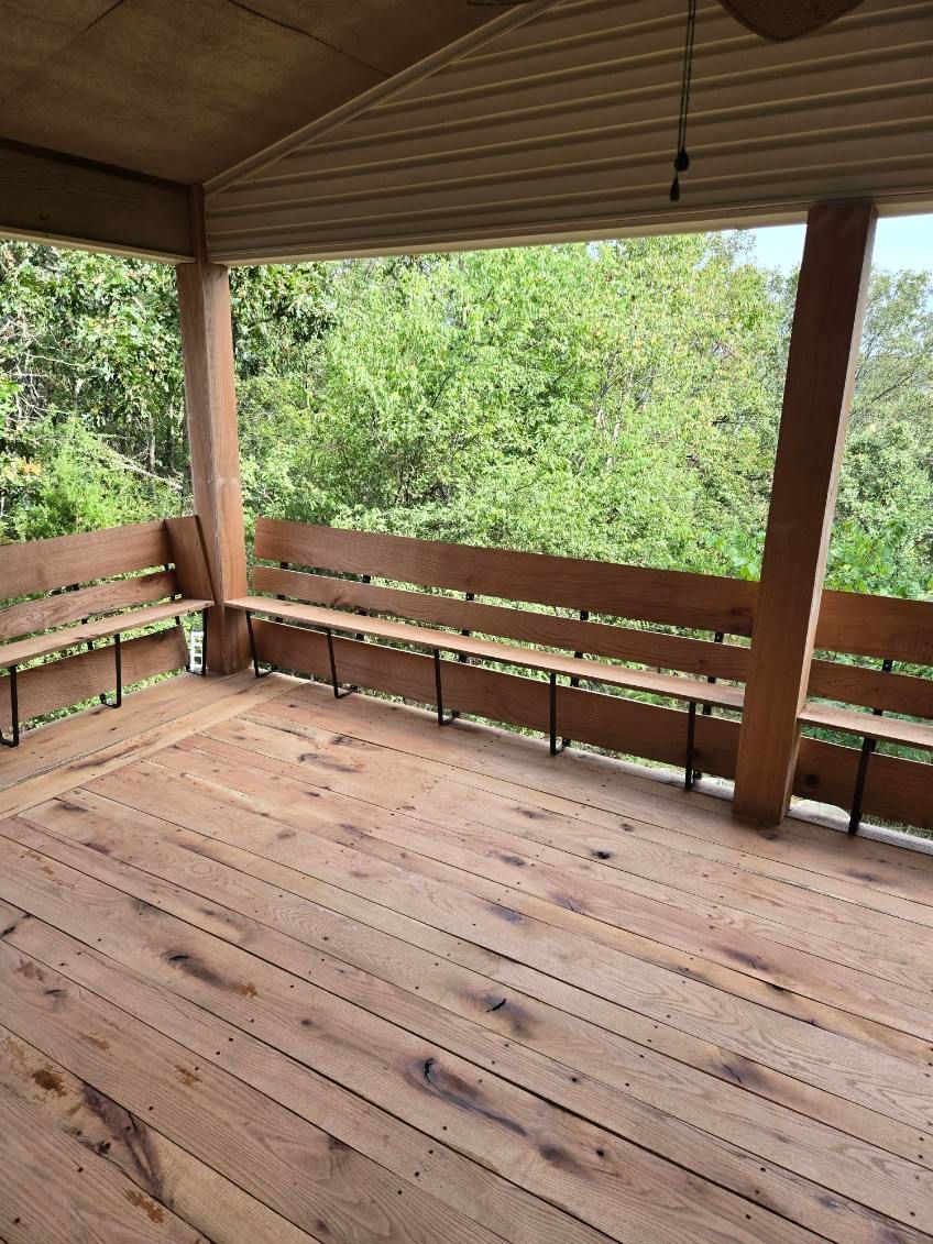 A wooden porch with benches and a ceiling fan.