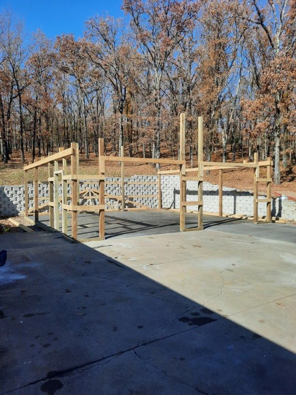 A wooden structure is being built in a parking lot with trees in the background.