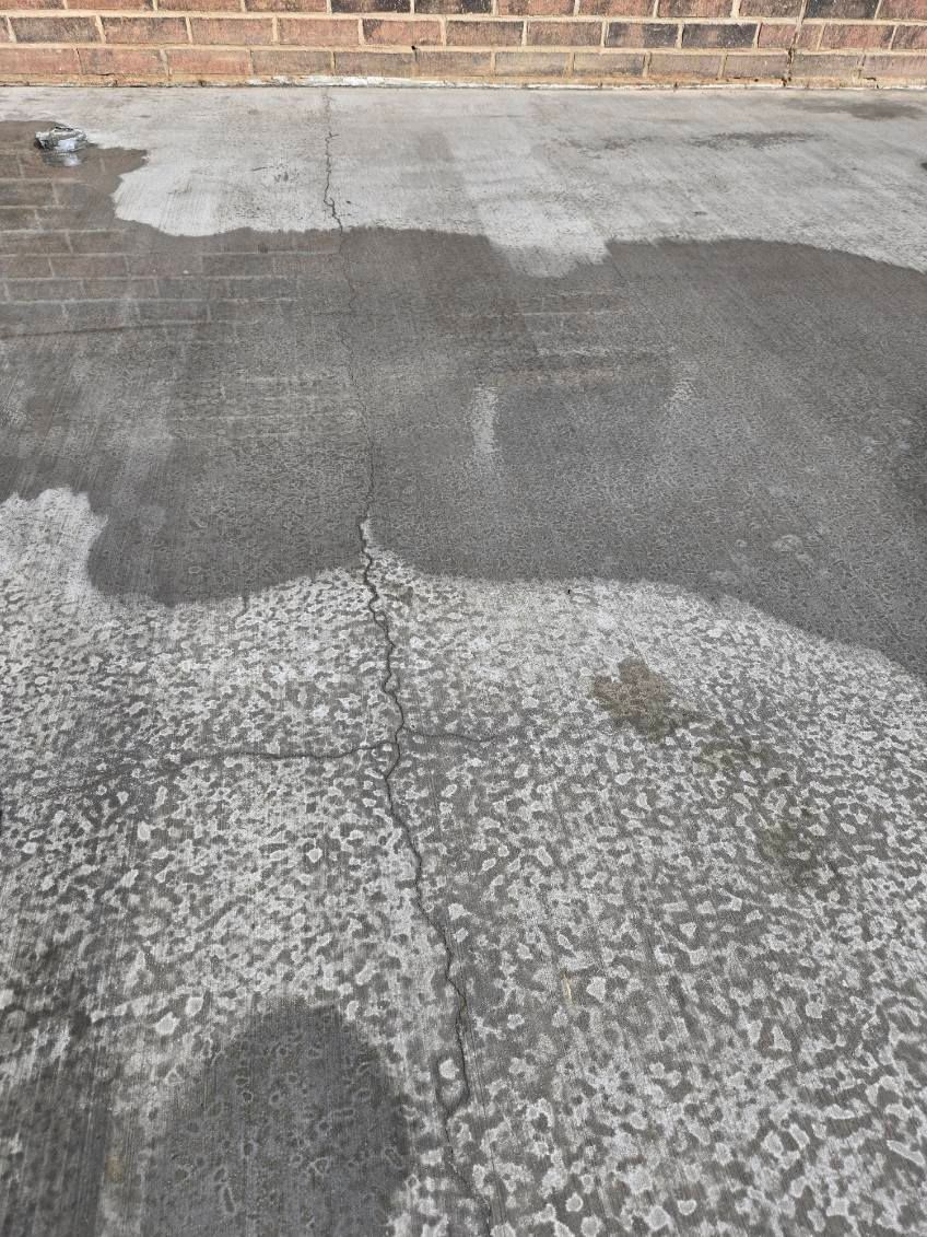 A concrete floor with a brick wall in the background
