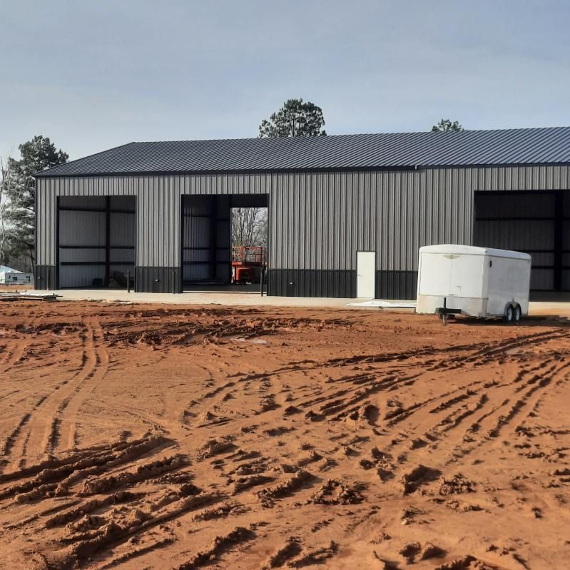 A trailer is parked in front of a metal building