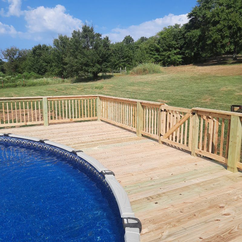 A swimming pool with a wooden deck and fence around it