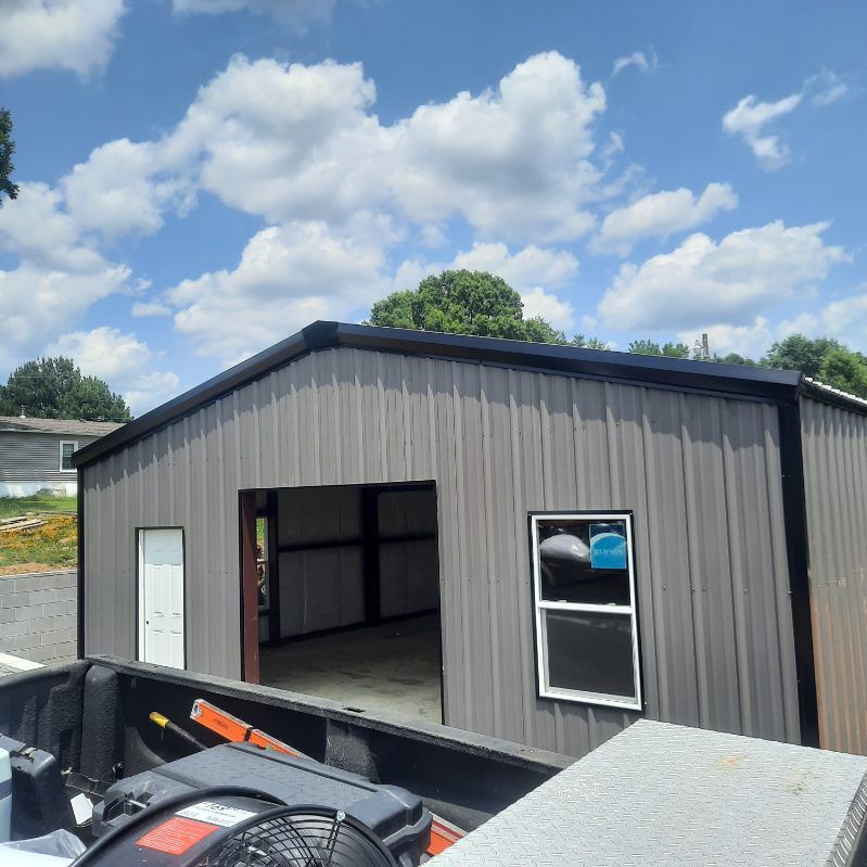 A metal building with a window and a fan in front of it