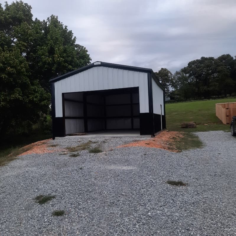 A white and black building is sitting in the middle of a gravel road