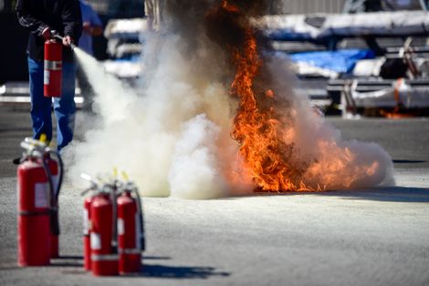 hand held fire extinguisher in action putting out a fire in a fire extinguisher training class.