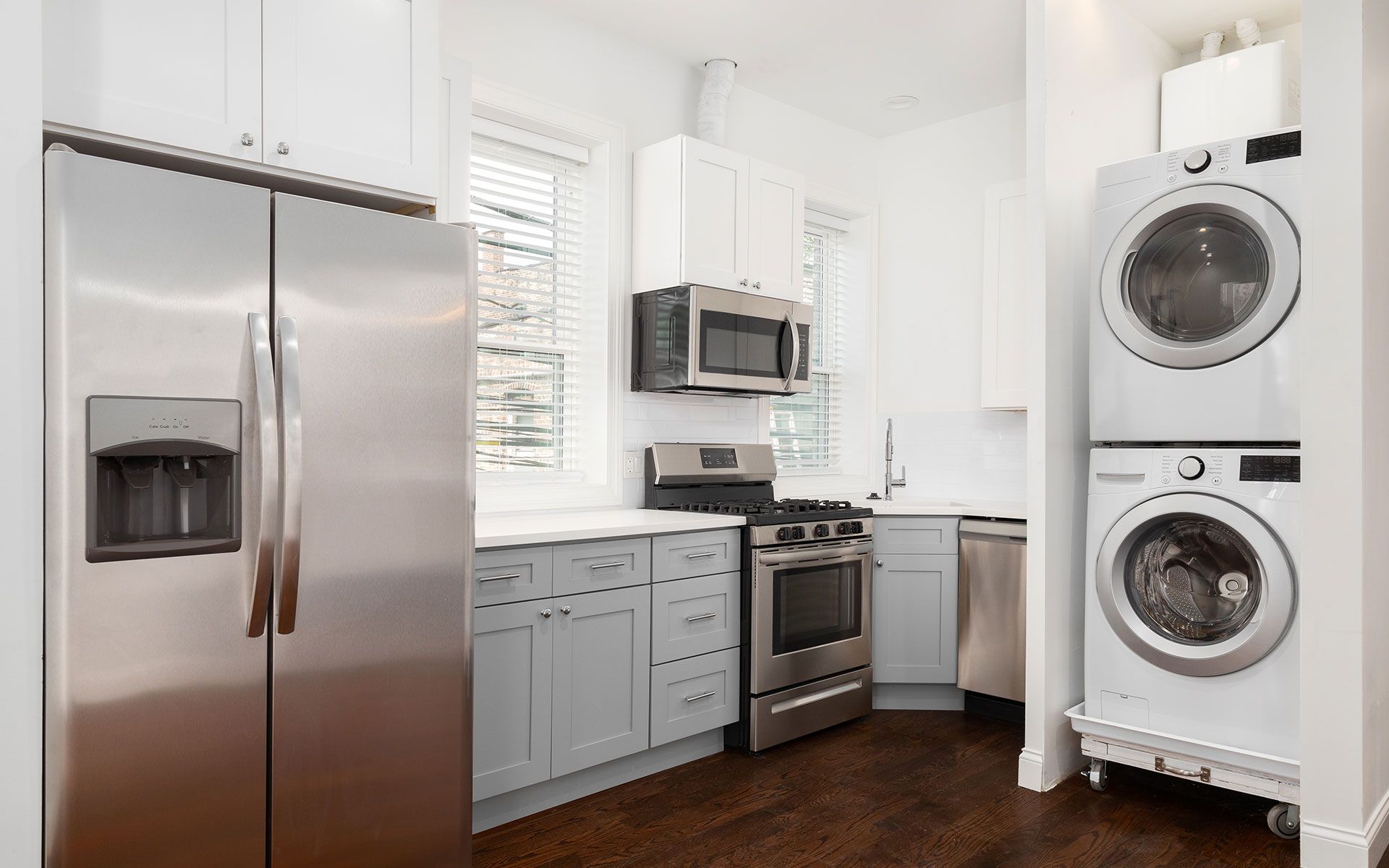 A small, bright kitchen featuring stainless steel appliances, gray and white cabinets.