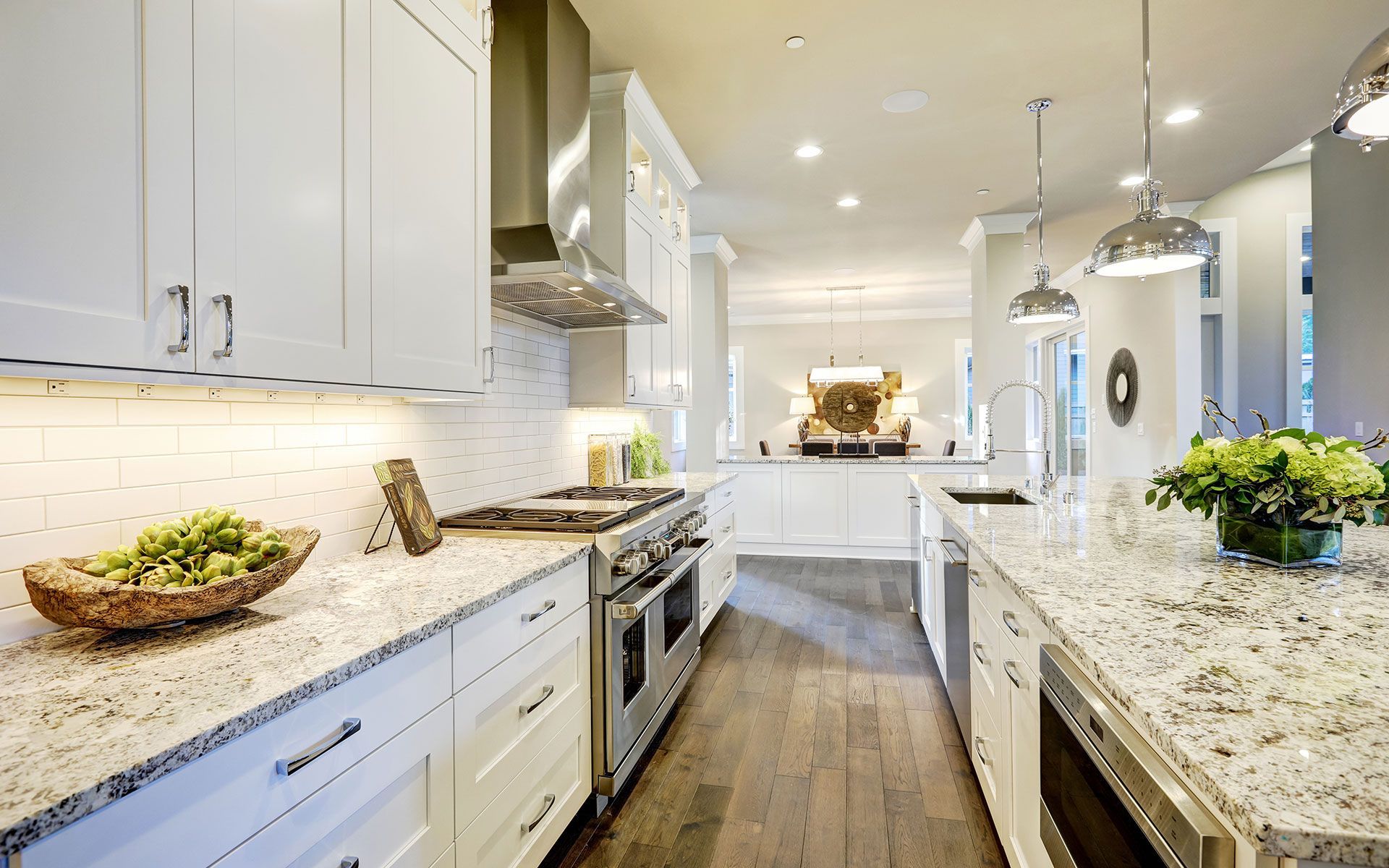 Bright white kitchen with granite countertops, stainless steel appliances, and wood flooring.
