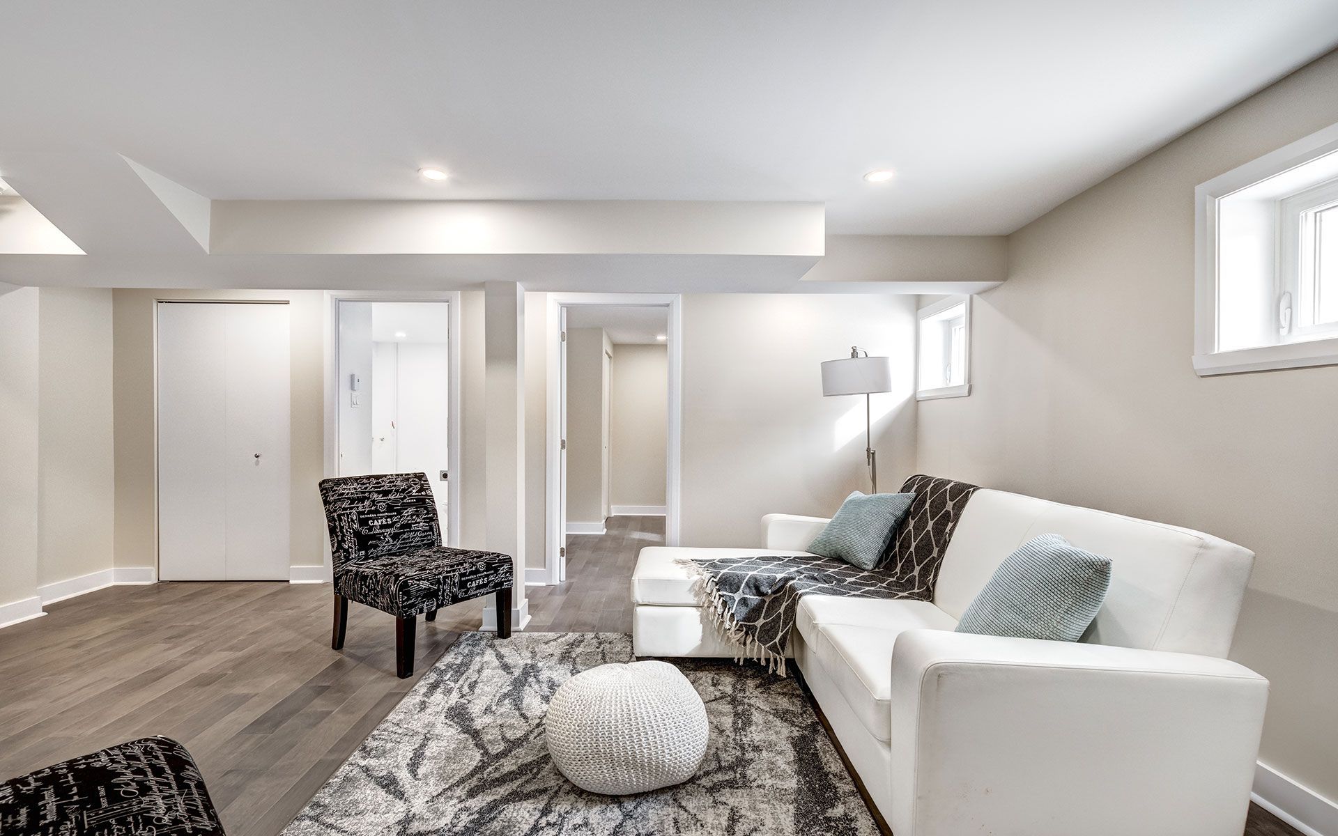A modern living room with white walls, a white sectional sofa.