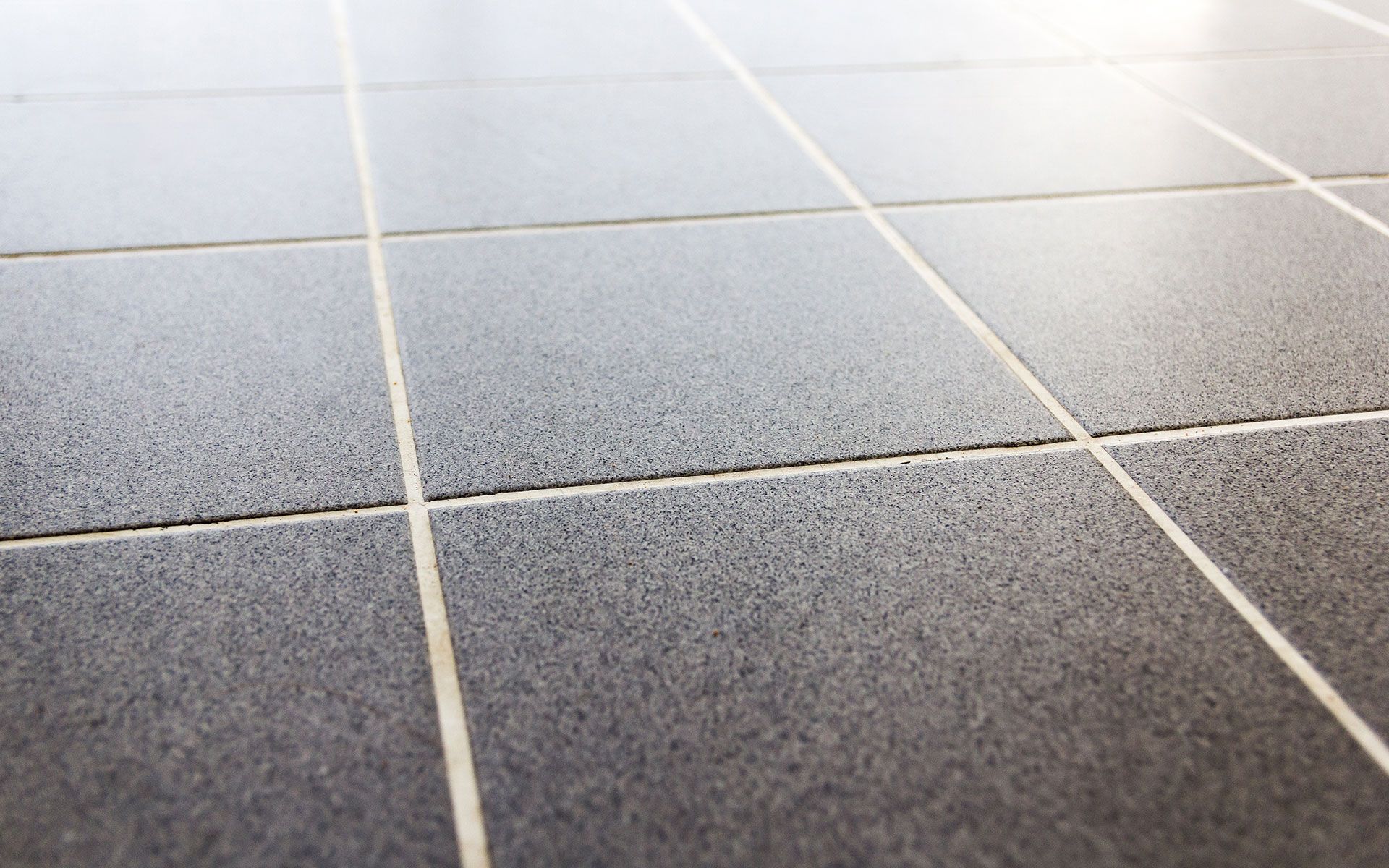Close-up view of gray tiled floor with white grout lines, angled perspective.