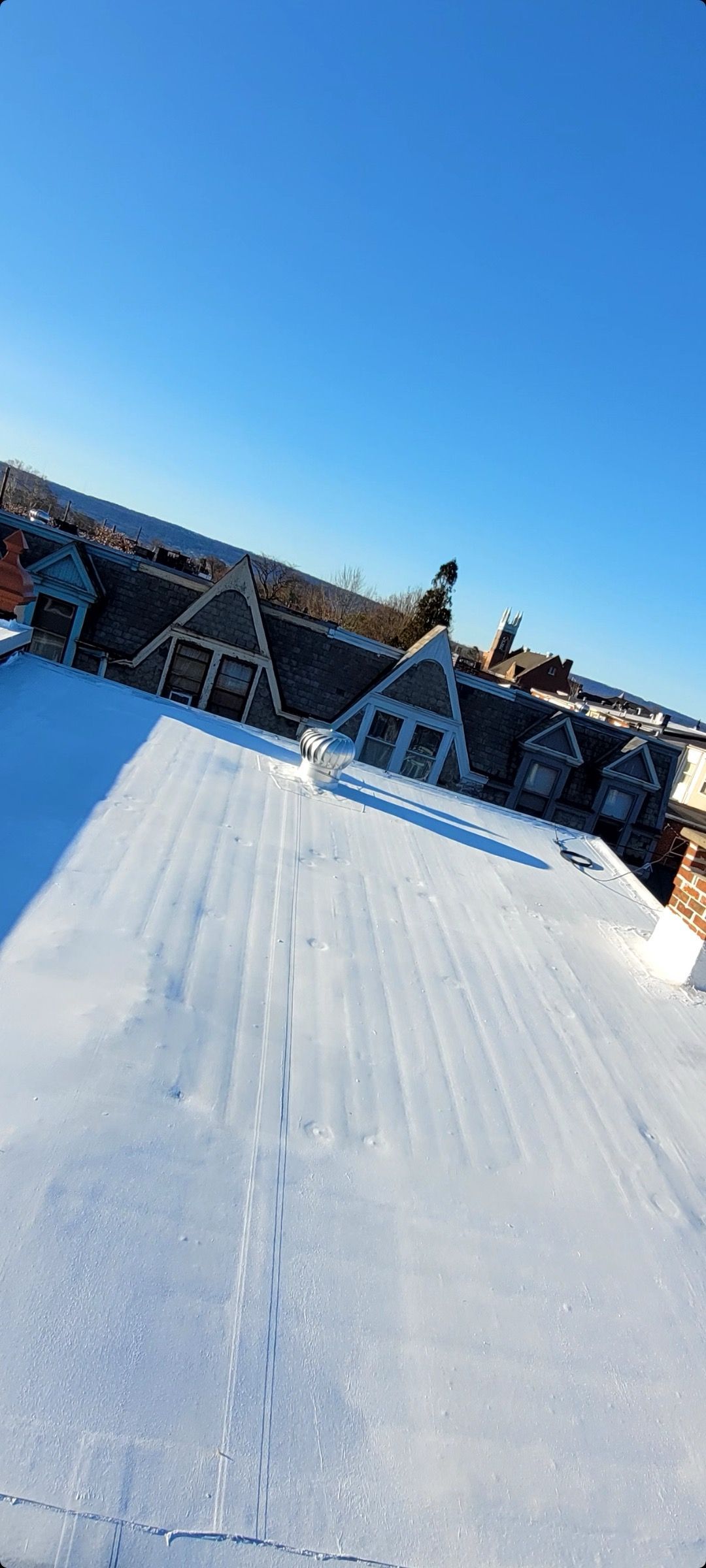 A snowy roof of a building with a blue sky in the background.