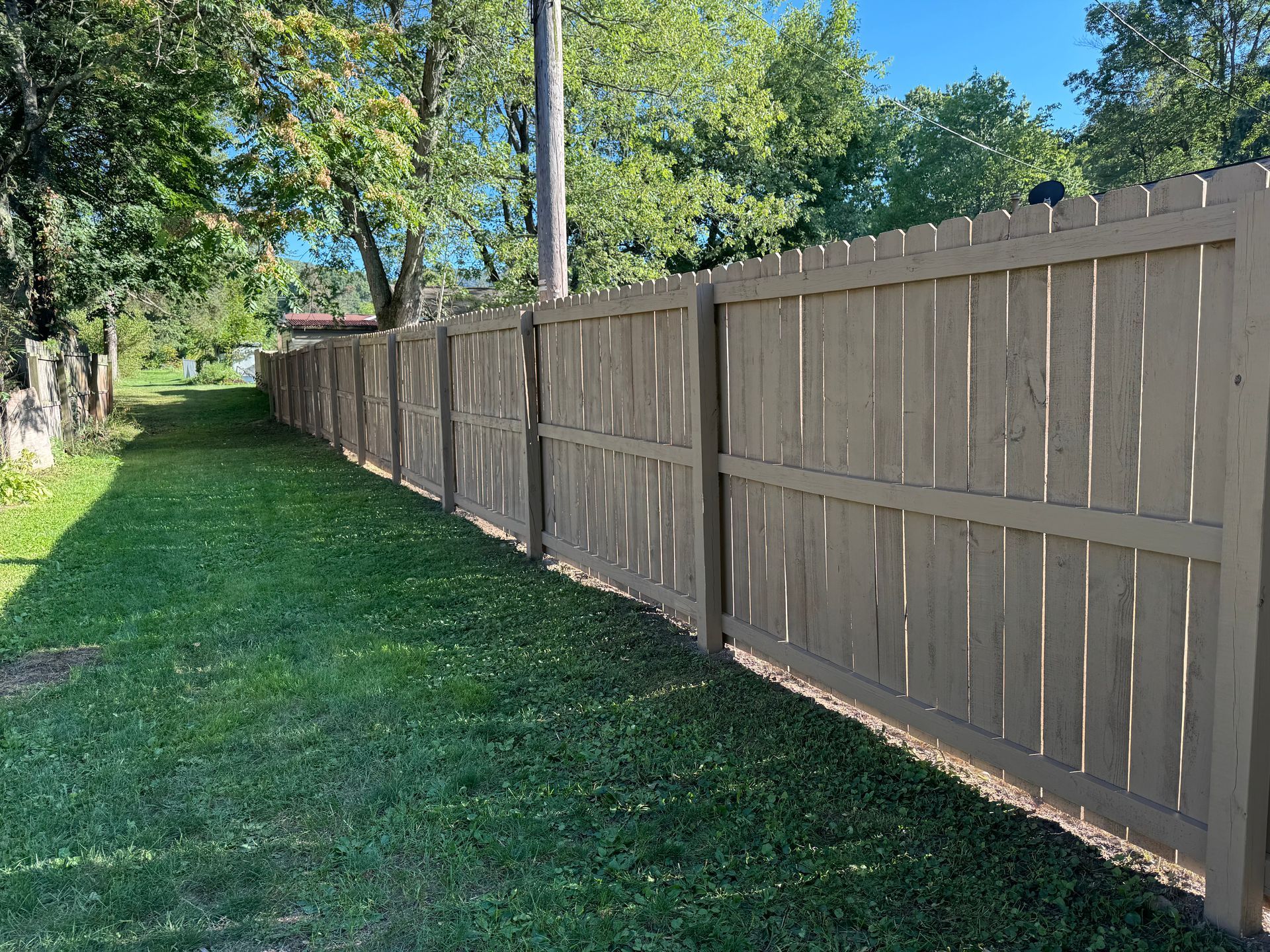 A wooden fence surrounds a lush green yard.