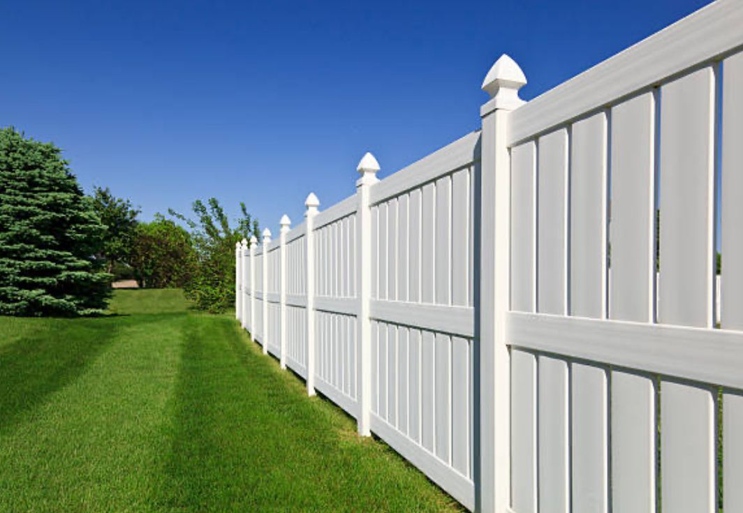 A white fence surrounds a lush green yard.