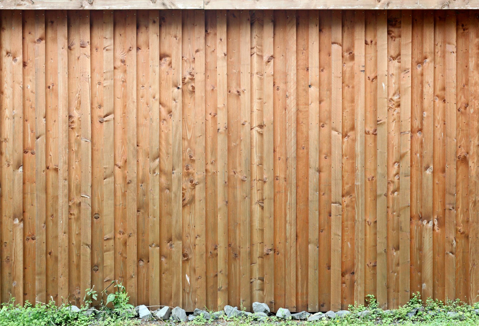 A wooden fence is surrounded by grass and rocks